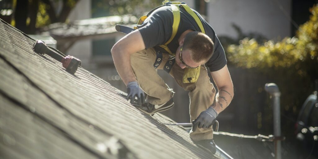 Roofer prepping a roof for new application of roof paint.